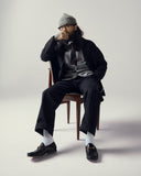 Model seated wearing stone-grey Harris cardigan with with overcoat.