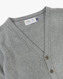 Front view of Uskees stone-grey lambswool Harris cardigan with focus on v-neck, corozo buttons and branding label.