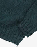 Close-up shot of an Uskees shadow marine (green) turtleneck sweater for men showing the ribbed cuff and hem.