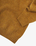 Close up view of Uskees 7021 Skye lambswool sweater in buckthorn (mustard yellow), with focus on the wool texture, hem and cuff.