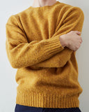 A person wearing a fuzzy mustard yellow knit sweater with crossed arms, shown from the neck down to waist against a plain light background.