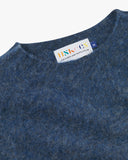Close up view of Uskees 7021 Skye lambswool sweater in sapphire blue, with focus on crew neck and branding label.