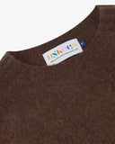 Close up shot of Uskees loam brown men's sweater showing the neckline and brand label.
