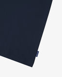View of hemline of Uskees navy blue cotton T-shirt with focus on cotton jersey fabric and blue 'USKEES' logo tab on the seam.
