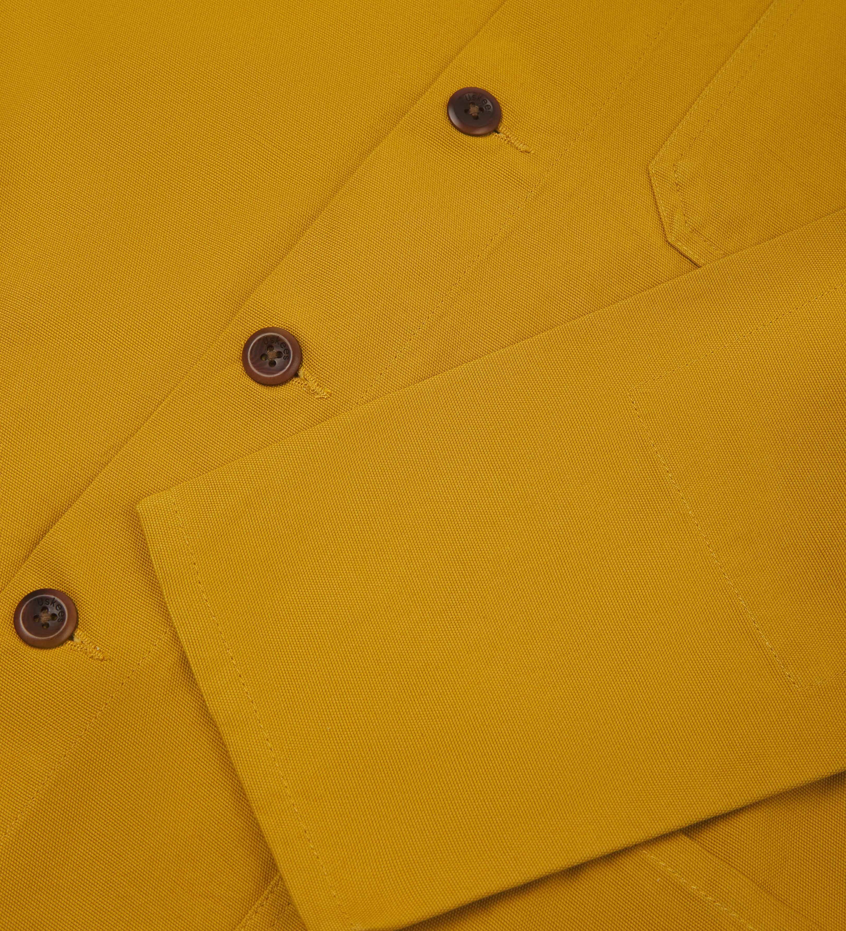 close up shot of sleeve and corozo buttons from a bright yellow, men's overshirt from Uskees