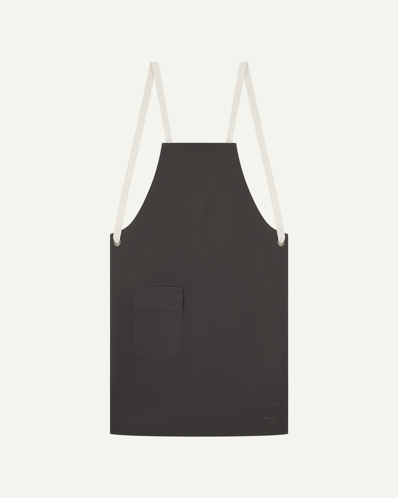 Flat shot of Uskees charcoal-grey canvas apron showing cream straps and front flap pocket.