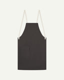 Flat shot of Uskees charcoal-grey canvas apron showing cream straps and front flap pocket.