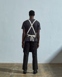 Full-length, rear view of model wearing Uskees 9001 coriander charcoal-grey work canvas apron by Uskees. Clear view of cream rear ties.