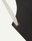 Close up shot of Uskees unisex charcoal-grey canvas apron showing cream strap.