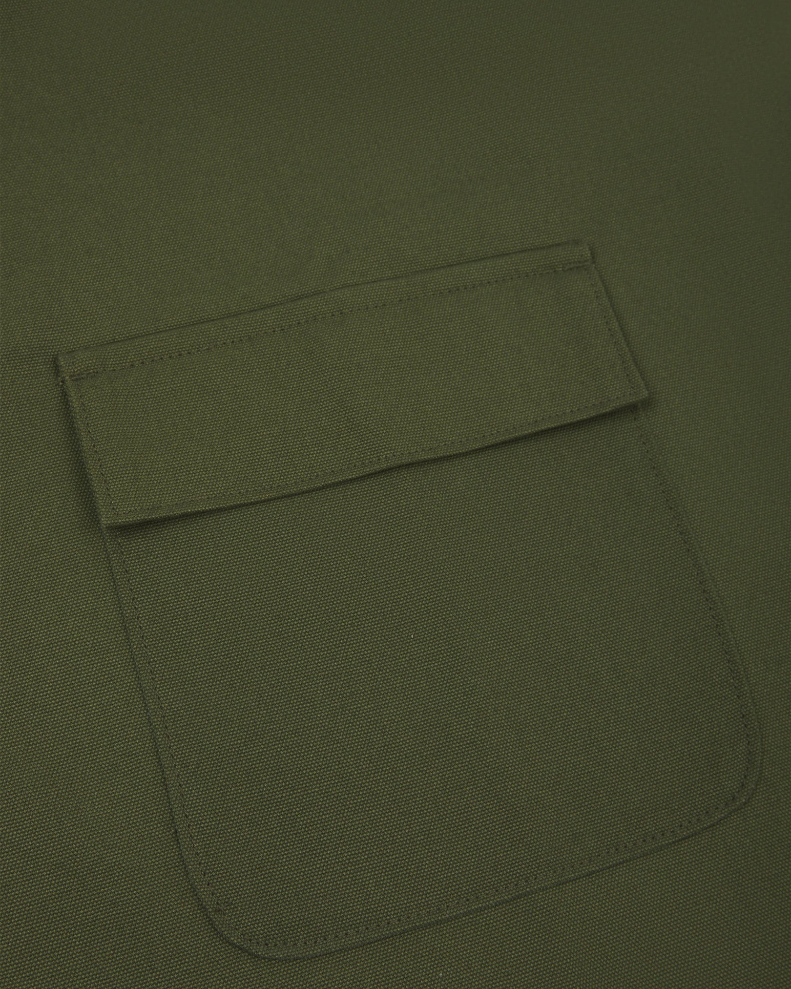 Close up shot of Uskees green canvas apron showing front flap pocket.