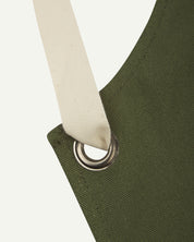 Close up shot of Uskees unisex green canvas apron showing cream strap.