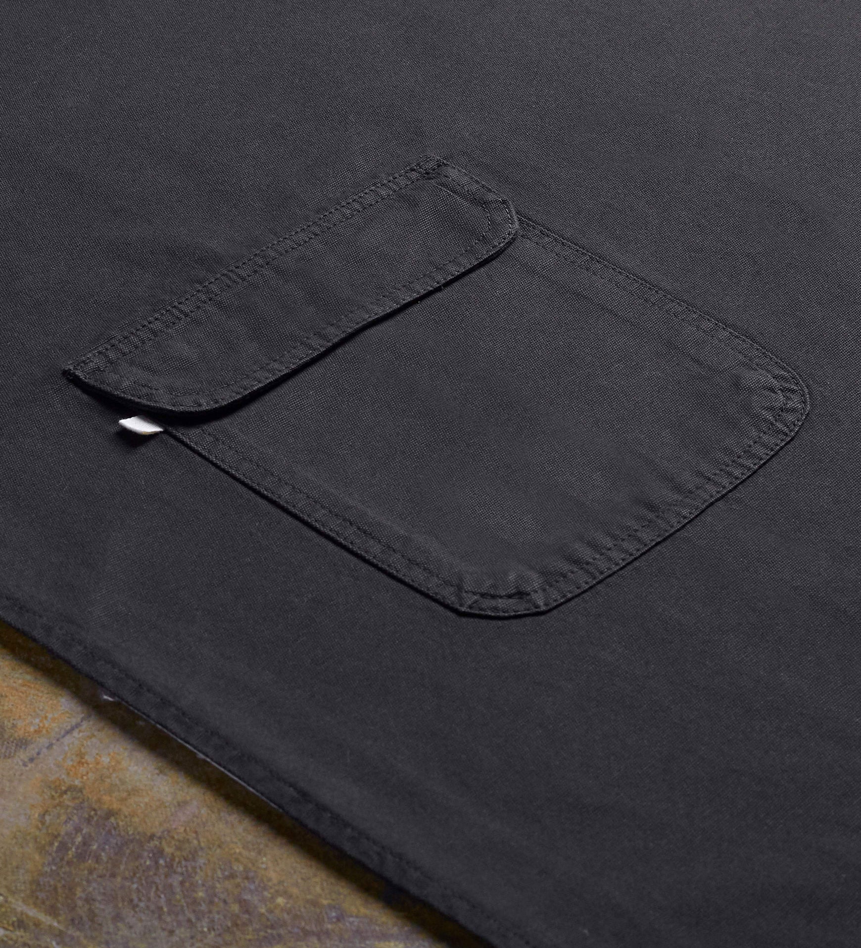 Angled flat view of faded black #9001 work apron by Uskees. Showing hip pocket and clearer view of organic cotton fabric texture.