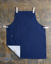 Full, flat view of navy #9001 work apron by Uskees. Showing hip pocket with left corner folded up to reveal lining and 'Uskees' label.