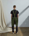 Full-length, rear view of model wearing Uskees #9003 khaki olive green Japanese-style apron by Uskees. Clear view of cross back design.