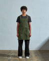 Full-length, front view of model wearing Uskees #9003 coriander-green Japanese style apron by Uskees.