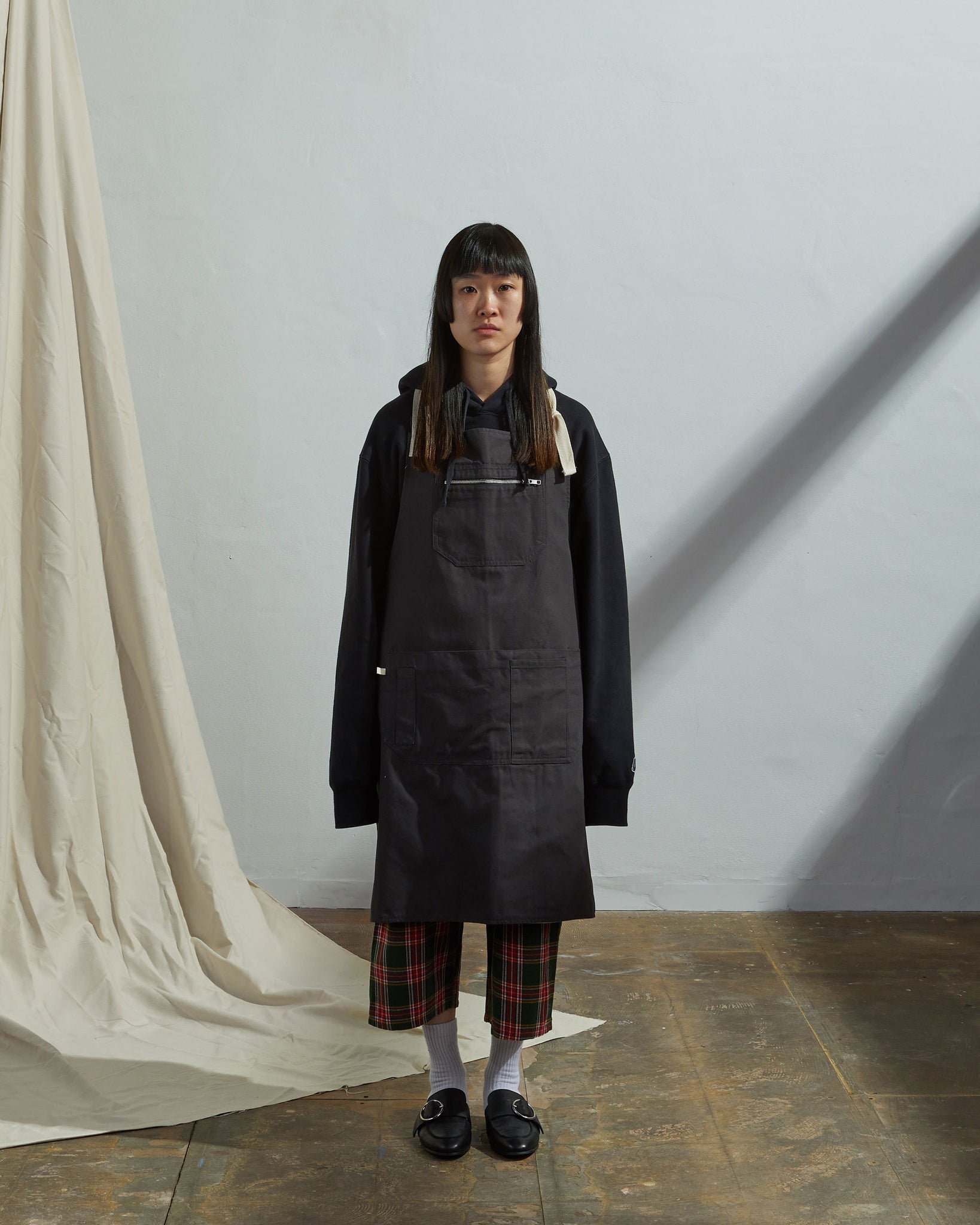 Full-length, front view of female model wearing unisex #9004 khaki carpenter-style work apron by Uskees.