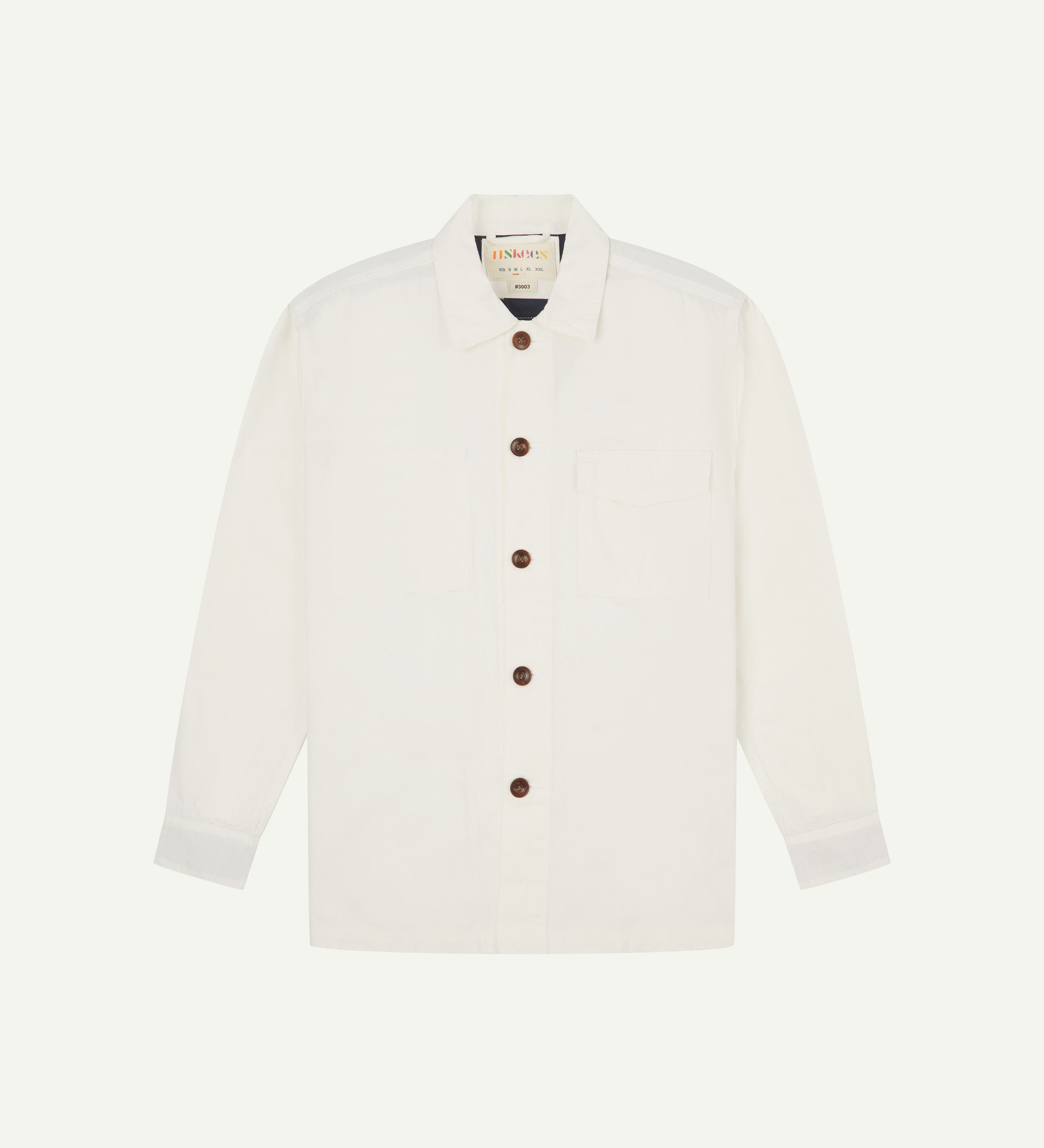 Front flat view of cream buttoned 3003 workshirt from Uskees. Showing breast pocket, navy yoke lining and brown corozo buttons