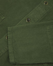 Front close shot of mid-green, buttoned corduroy overshirt from Uskees. Clear view of green corozo buttons and sleeve