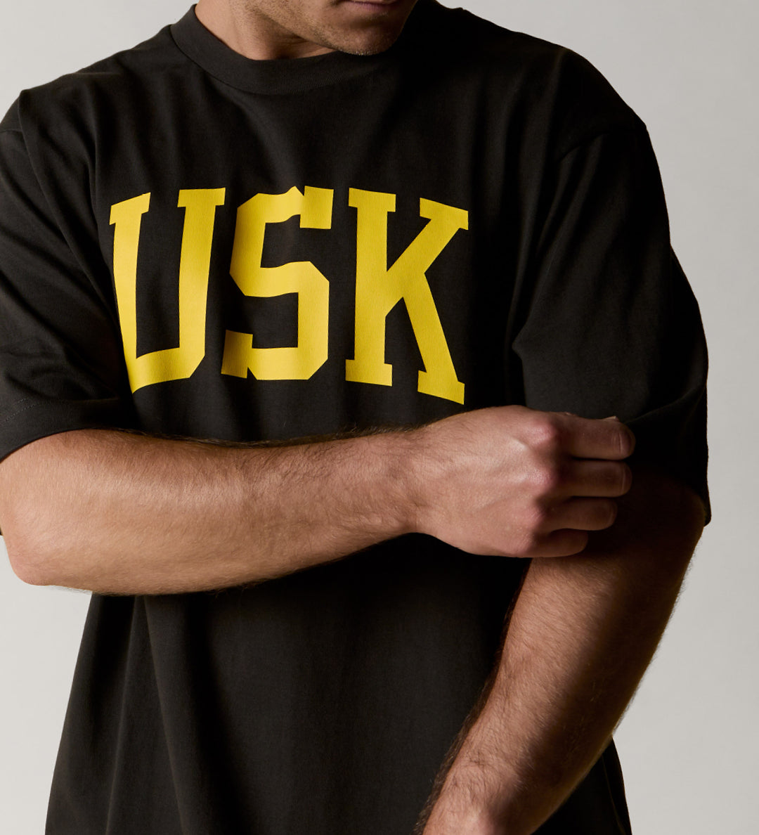 front model shot of uskees signature oversized Tee in faded black showing the yellow USK logo on the front.