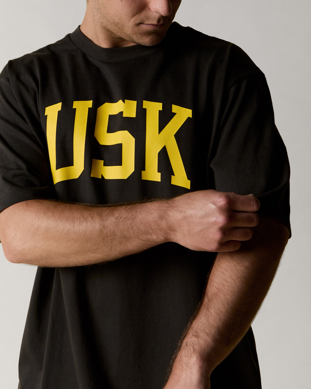 front model shot of uskees signature oversized Tee in faded black showing the yellow USK logo on the front.