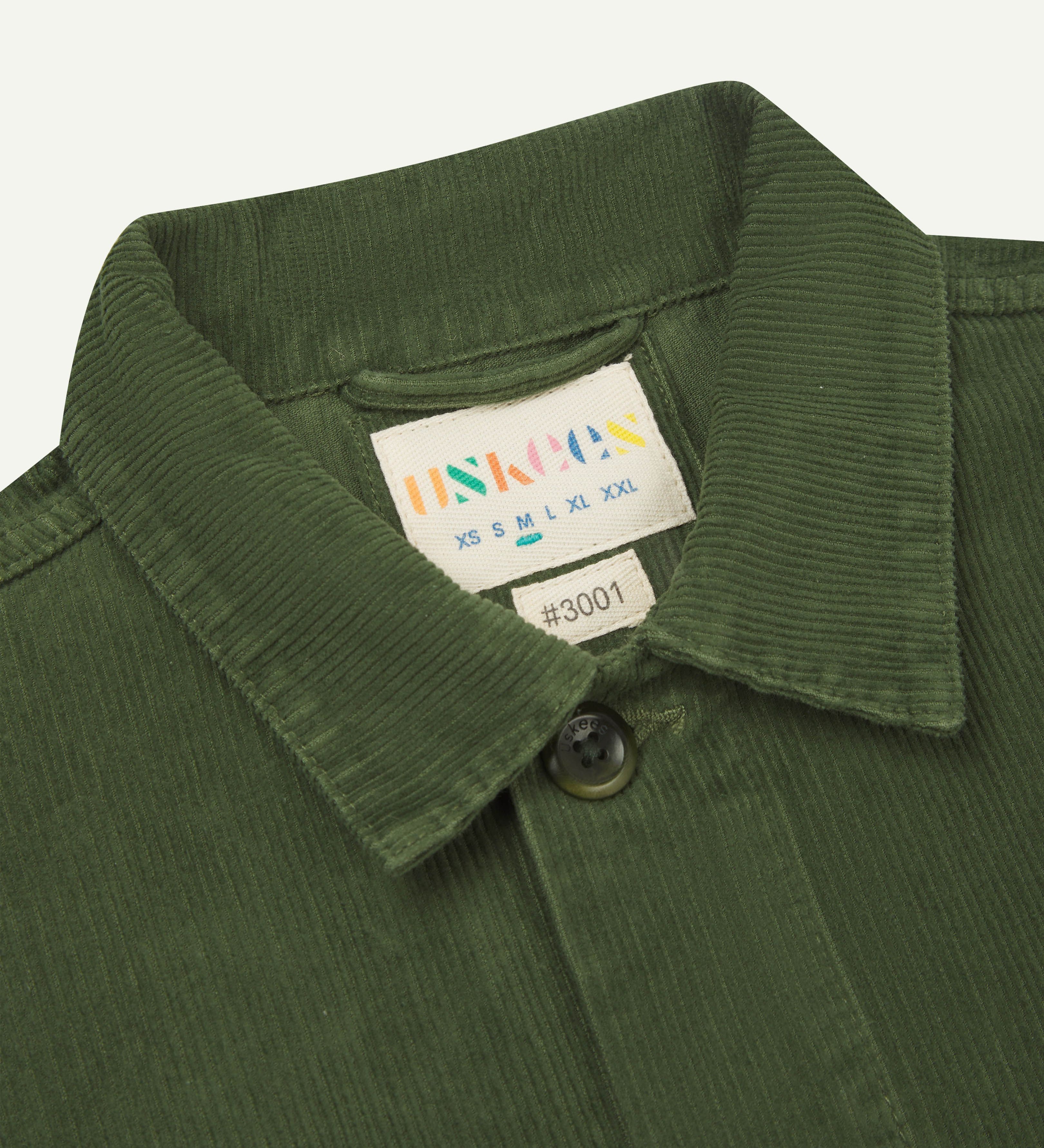 Front close-up shot of mid-green, buttoned corduroy overshirt from Uskees. Clear view of collar and neck label.