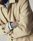 Male model wearing a beige Uskees car coat and pale blue shirt, against a neutral background