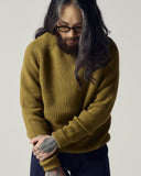 Male model wearing an Uskees woodland green ribbed sweater  and midnight blue trousers.