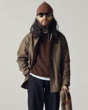 Male model wearing an Uskees brown shacket, loam brown sweater, and beanie with sunglasses on a plain background