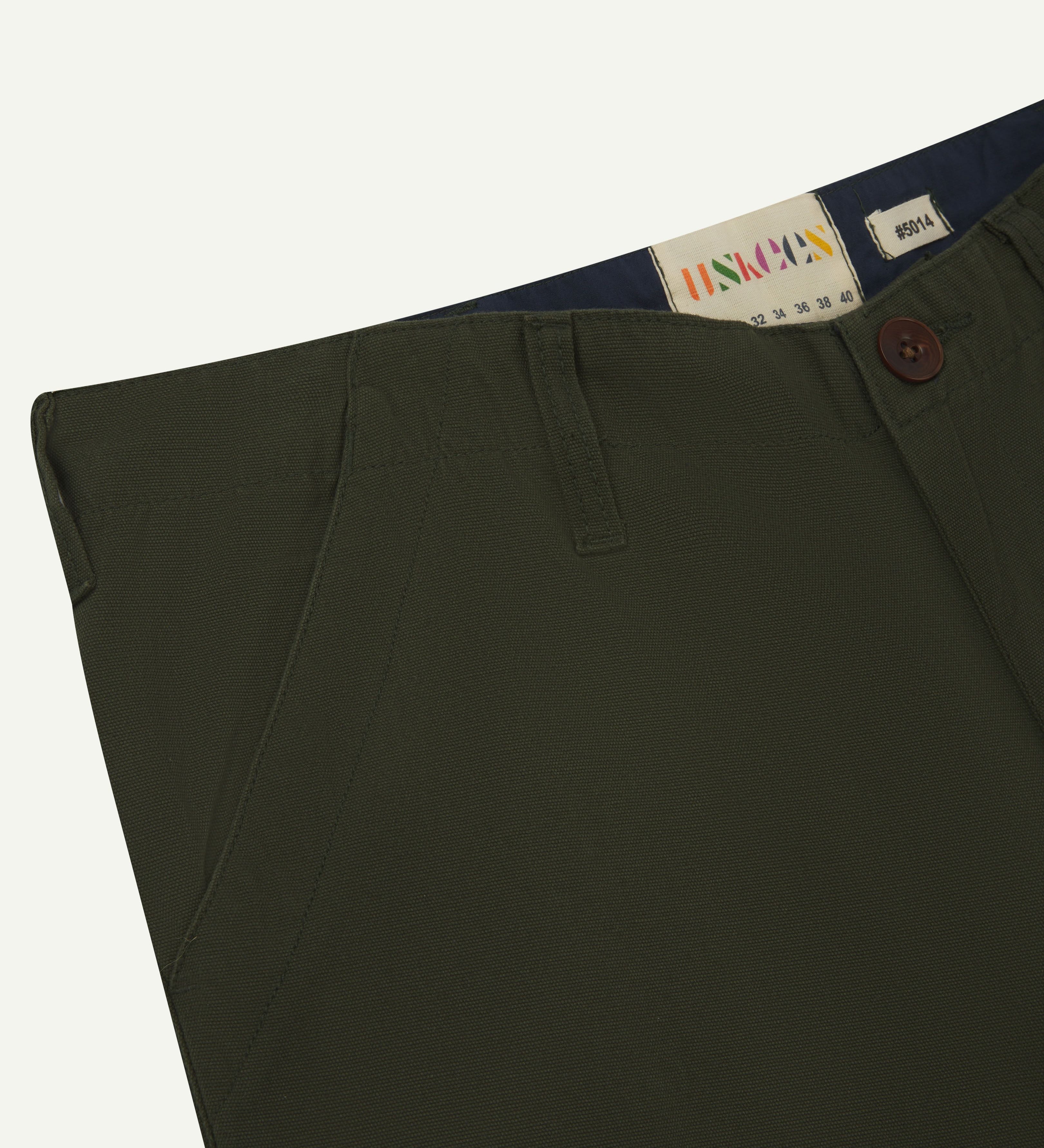 Close up view of #5014 Uskees men's organic cotton 'vine green' cargo trousers showing size label and front pocket