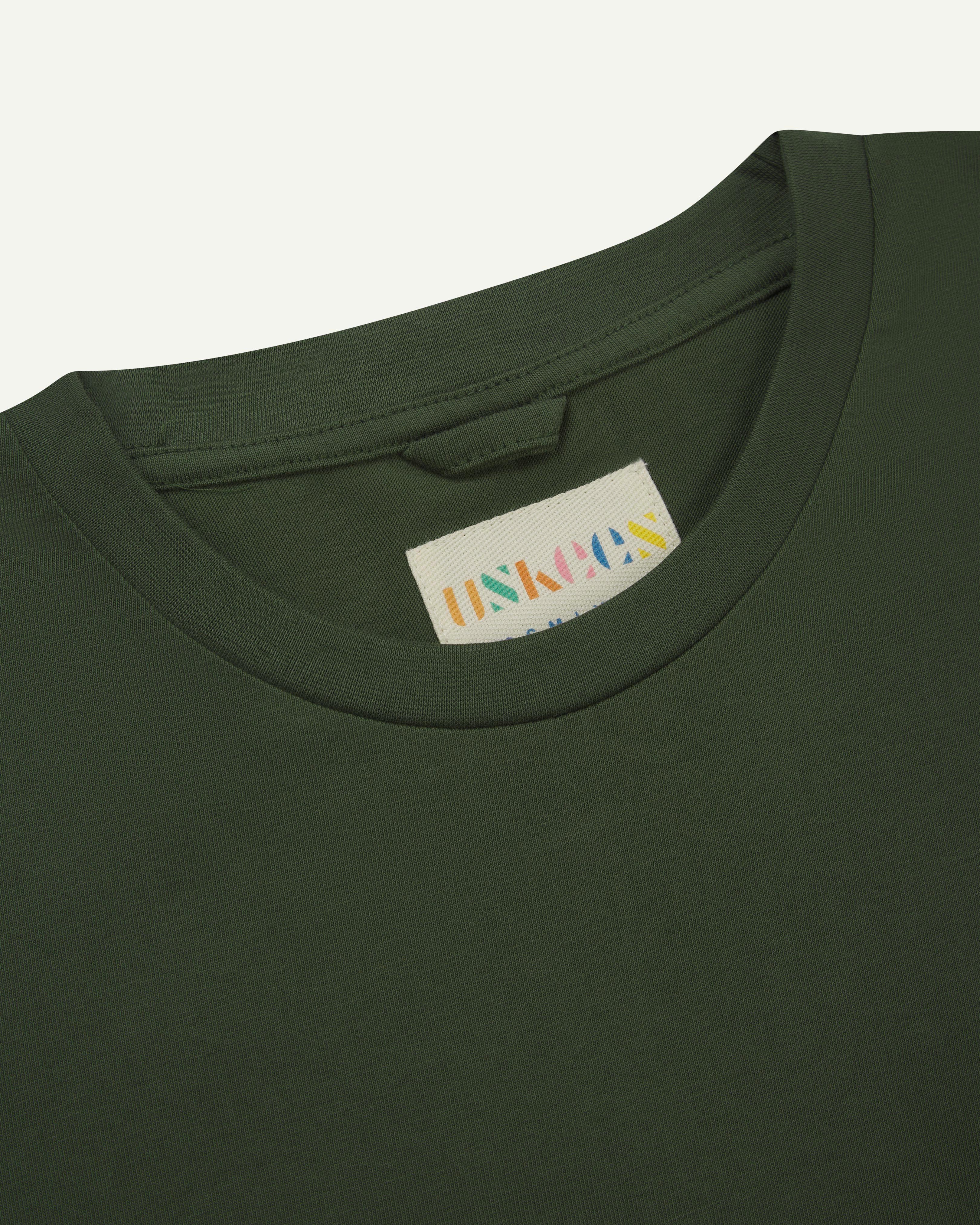 Close-up front shot of Uskees #7010 long sleeve t-shirt in coriander green showing Uskees branded label on inside neck.