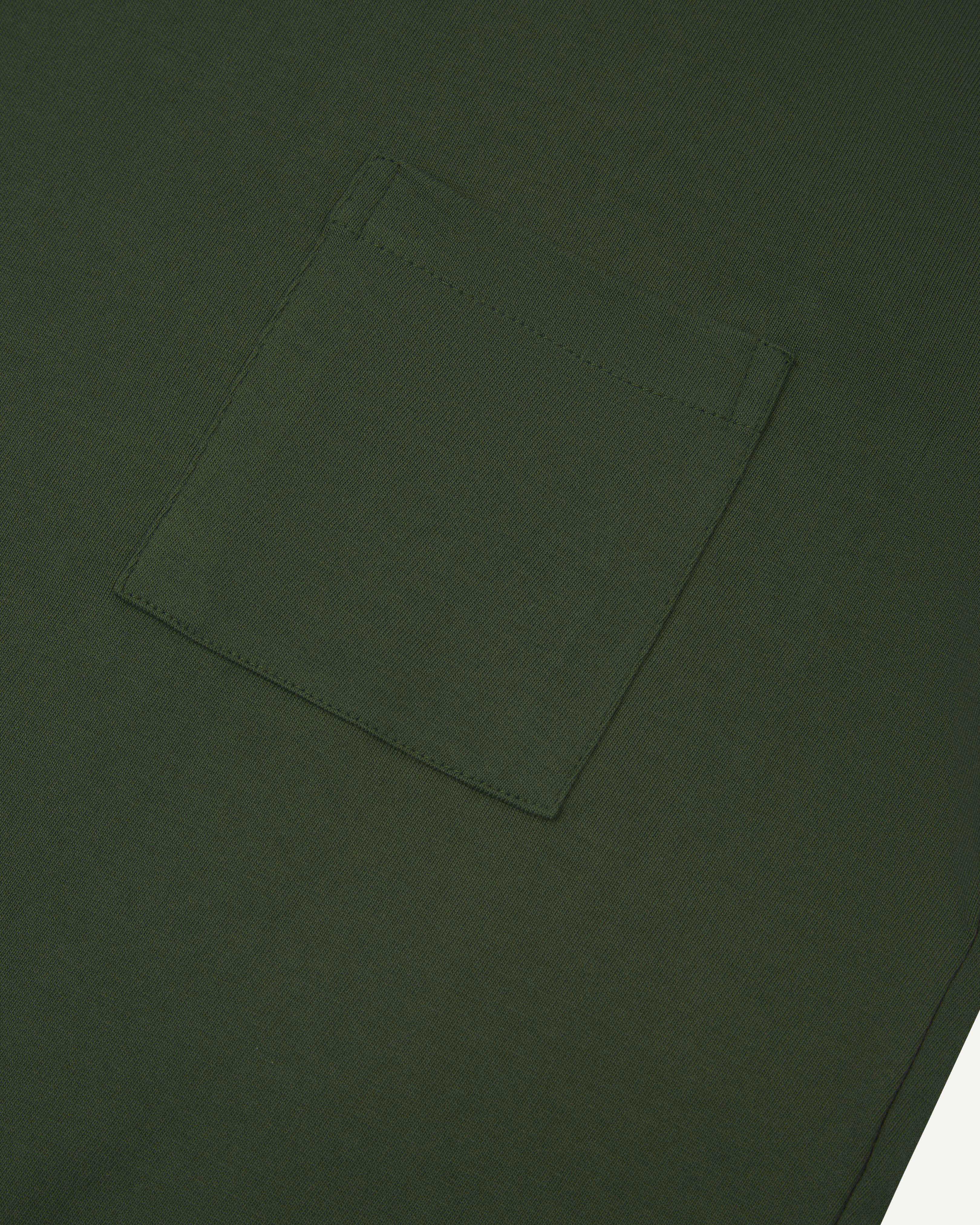 Close-up shot of Uskees #7010 long sleeve t-shirt in coriander green showing front breast pocket