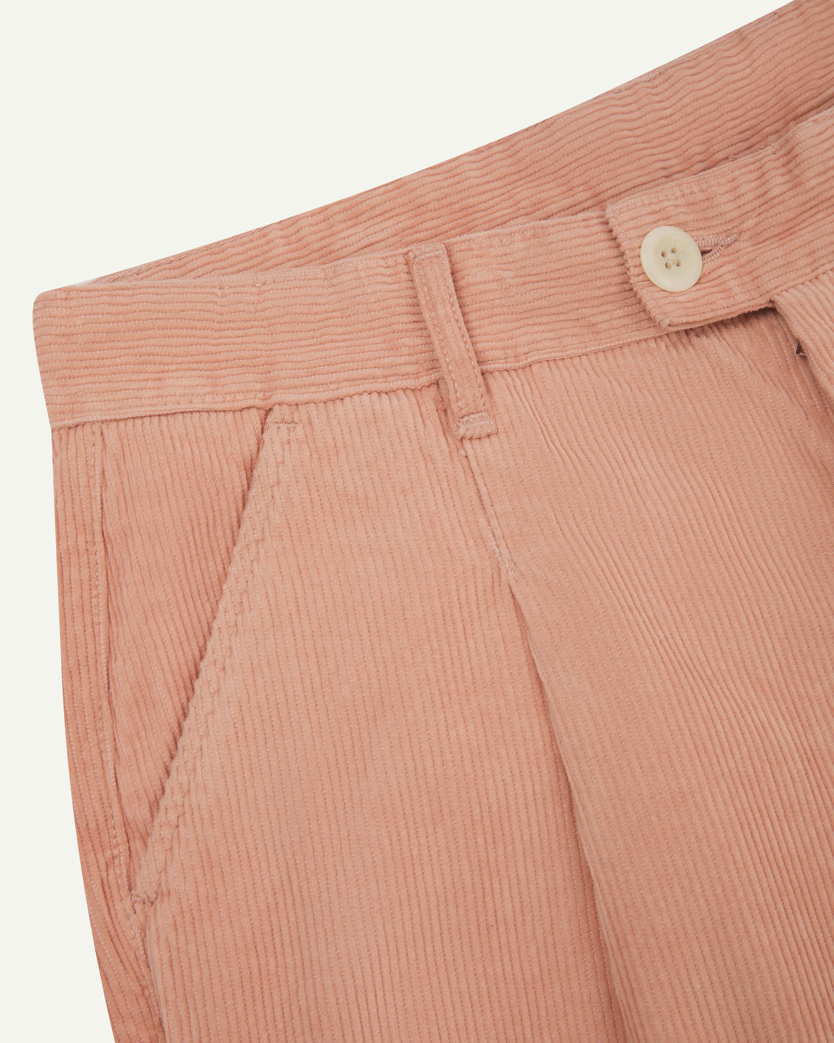 Front close-up shot of #5018 Uskees men's organic corduroy boat trousers in dusty pink showing belt loops, buttoned fastening and slanted front pocket.