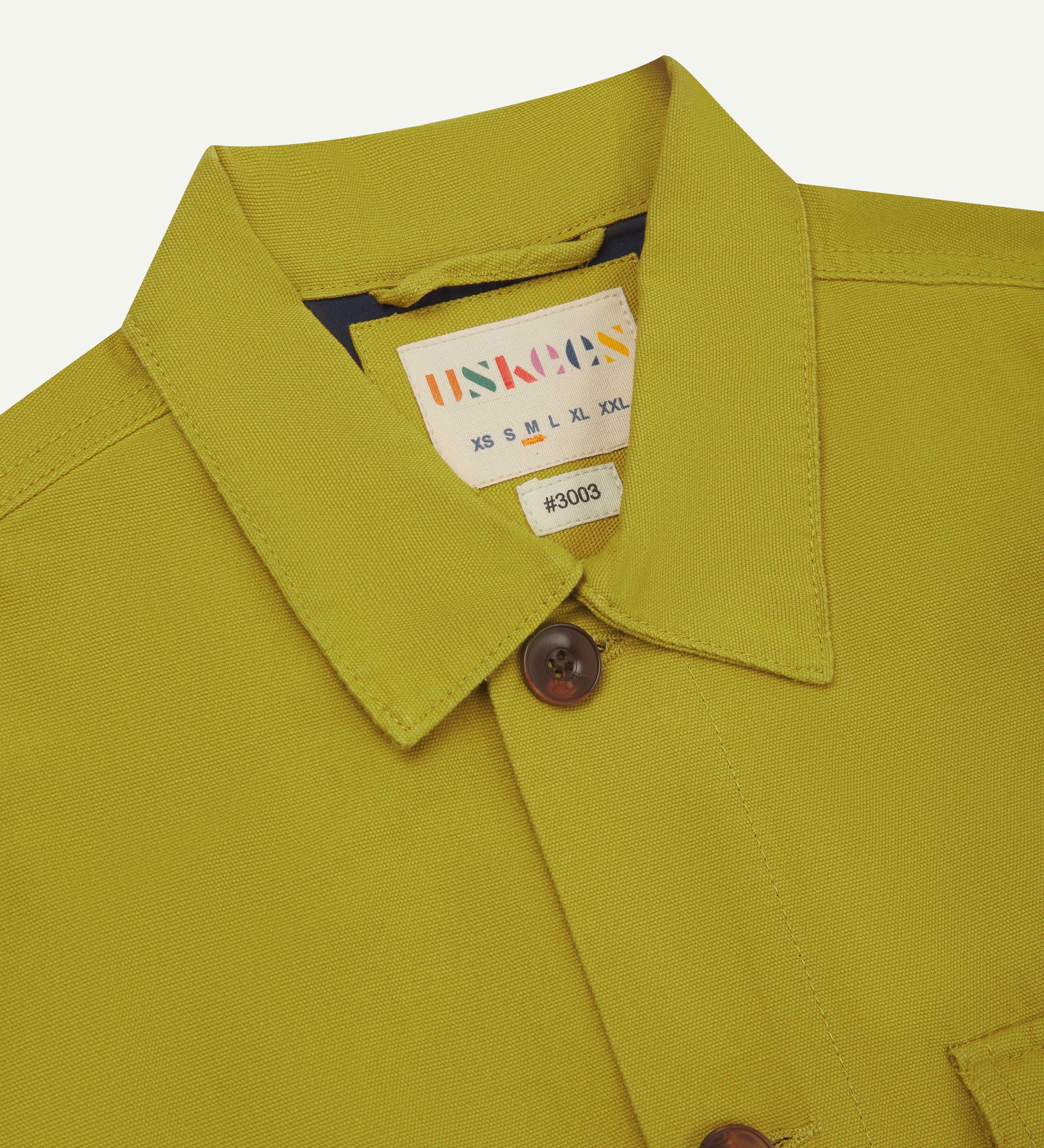 Front close up shot of uskees pear green workshirt for men showing brand label at neck and corozo button fastening