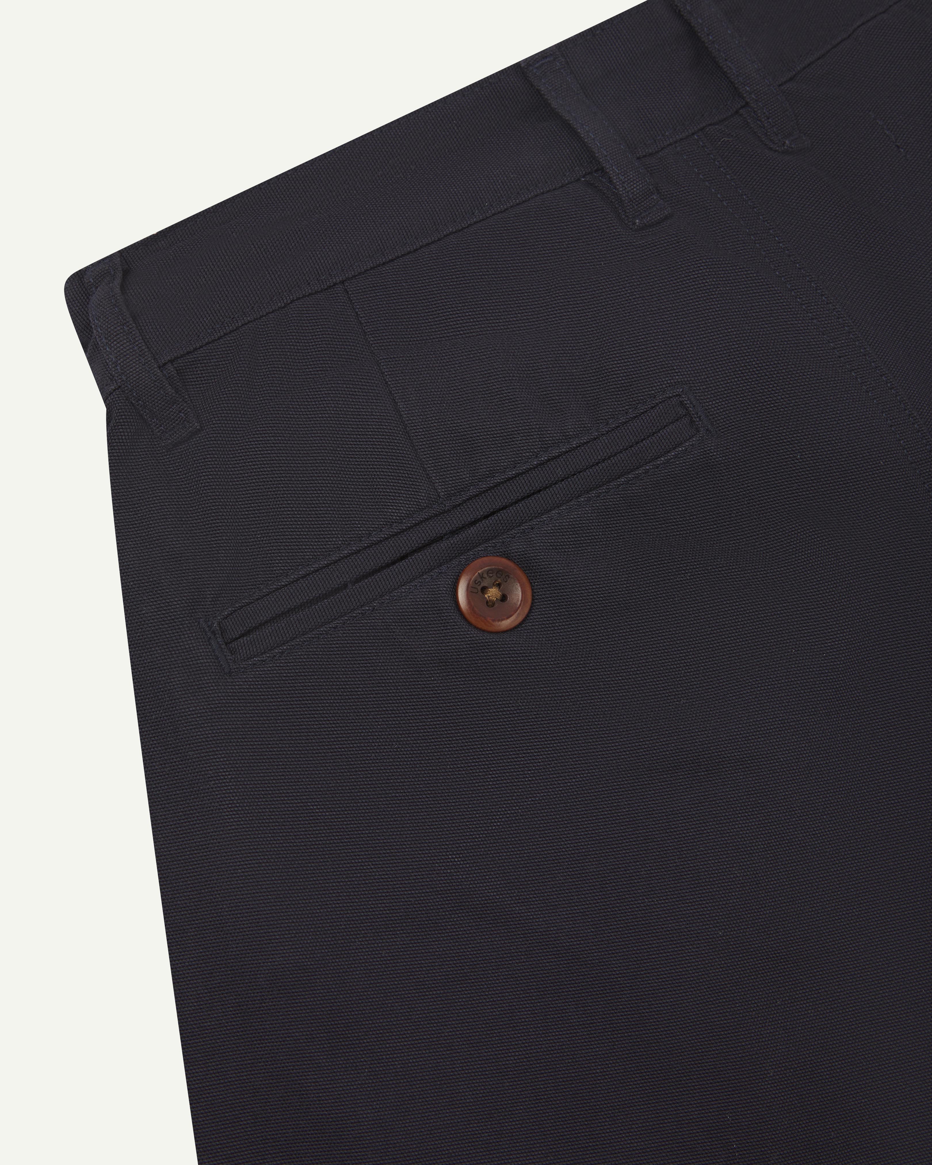 Close-up back view of #5018 Uskees men's organic cotton boat trousers in dark blue showing belt loops and buttoned back pocket.