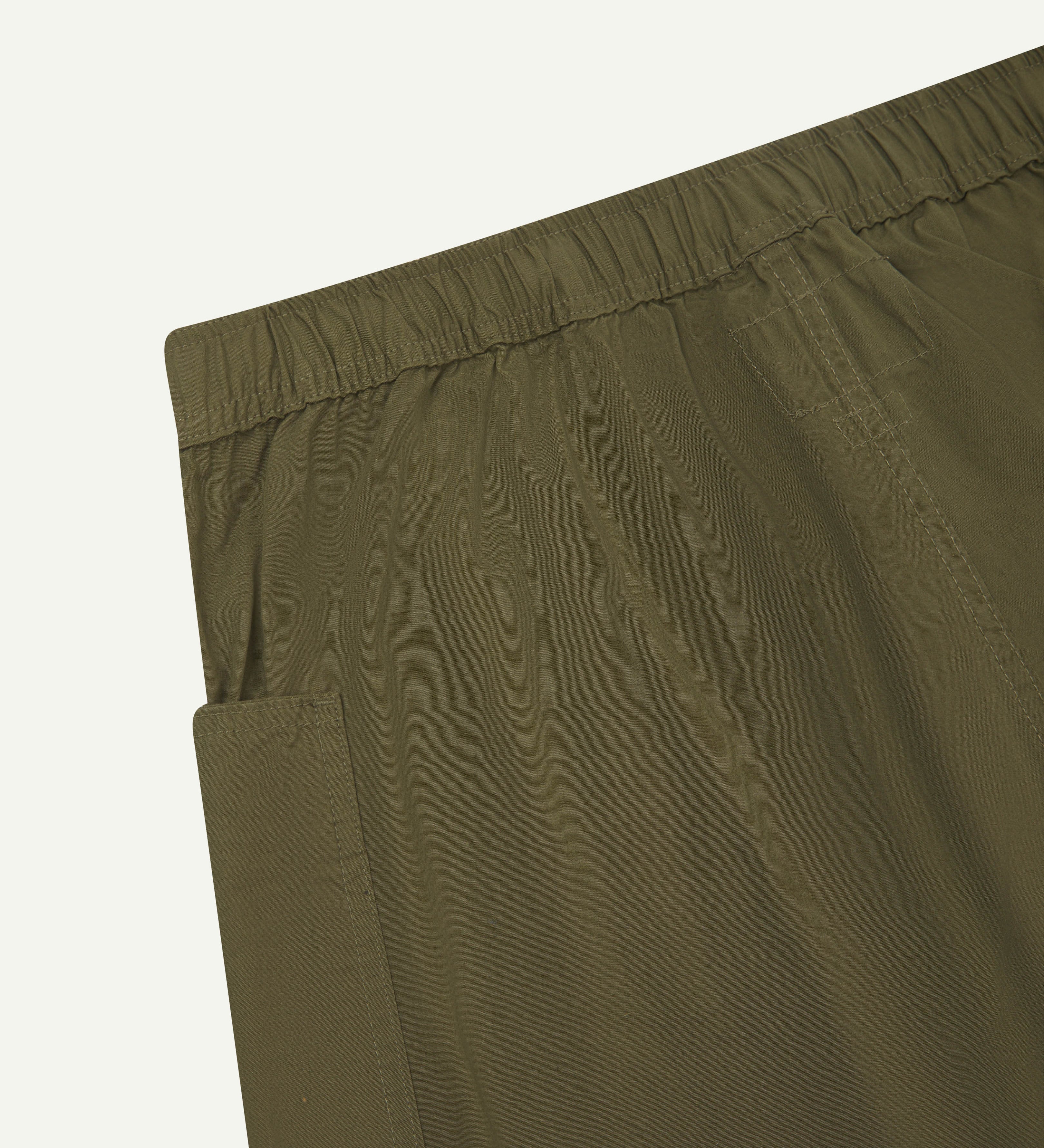Close-up of the back of the lightweight organic olive green cotton pants showing the elasticated waist.