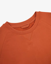 Close-up view of crew neck collar with decorative v-insert on Uskees cinnamon-red heavyweight cotton jersey sweatshirt.