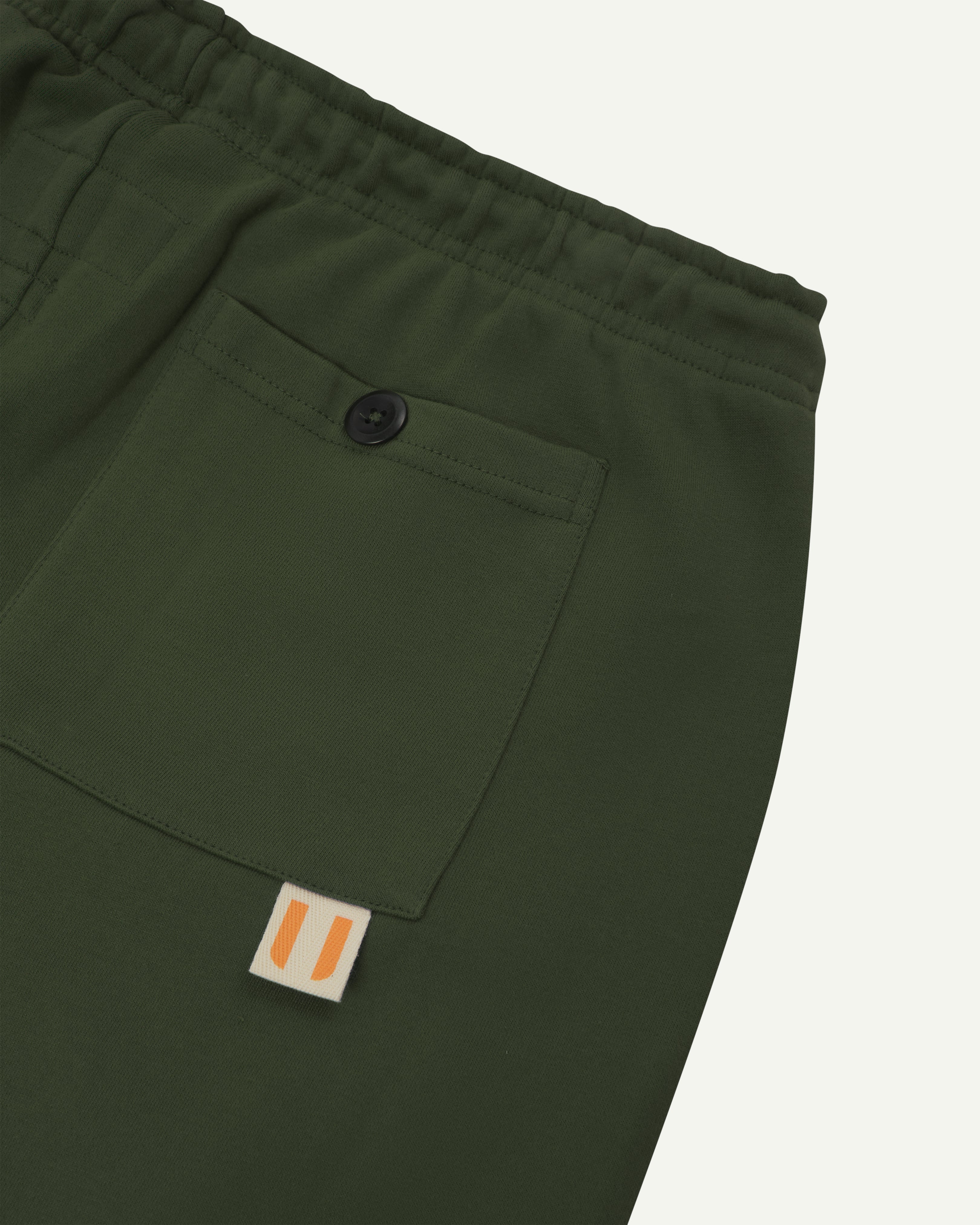 Back close view of organic cotton Joggers for men by Uskees showing the buttoned back pocket and logo label.