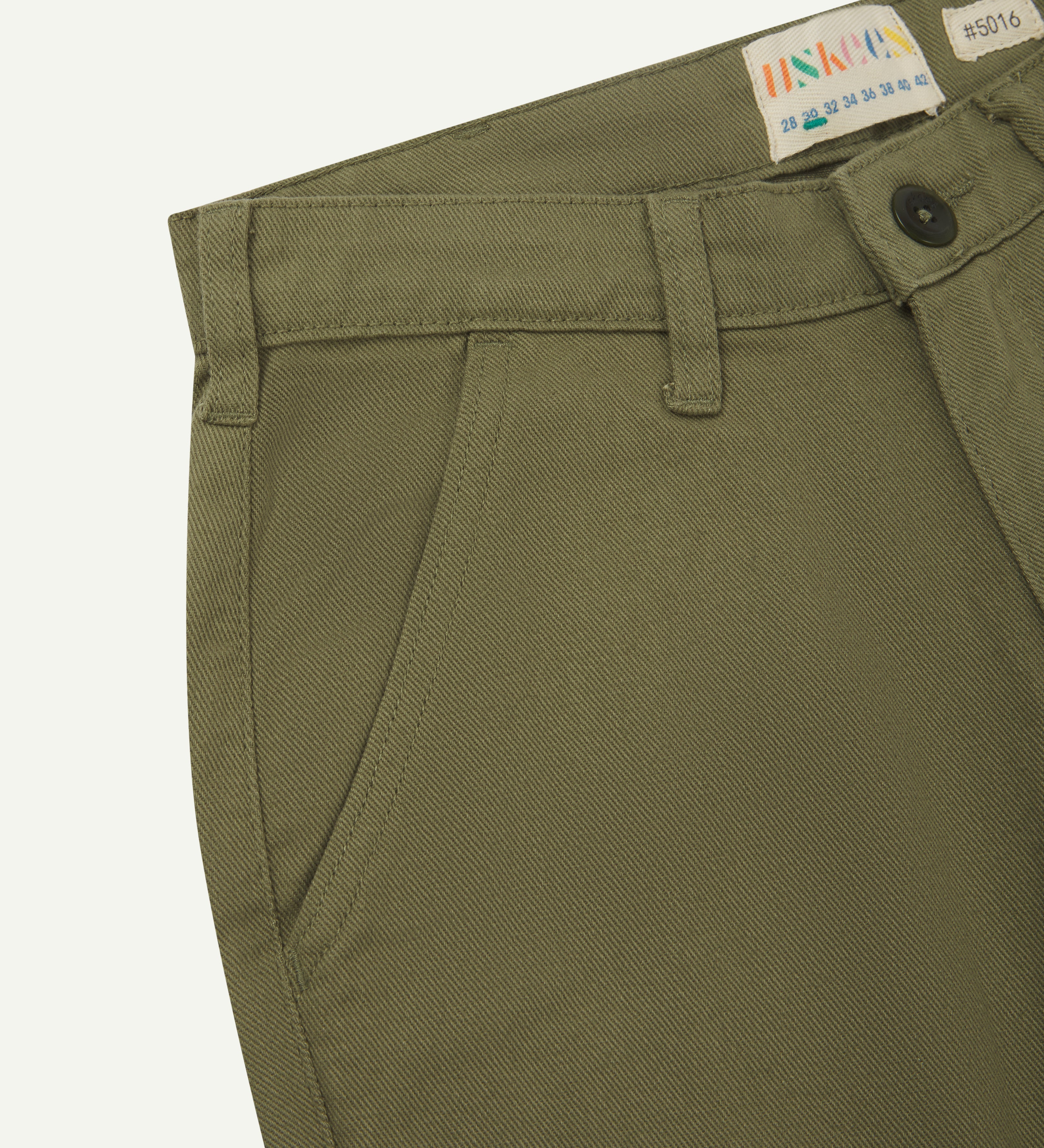 Front close view of uskees cotton drill 'commuter' trousers for men in moss green showing belt loops, front pocket and brand label at waist