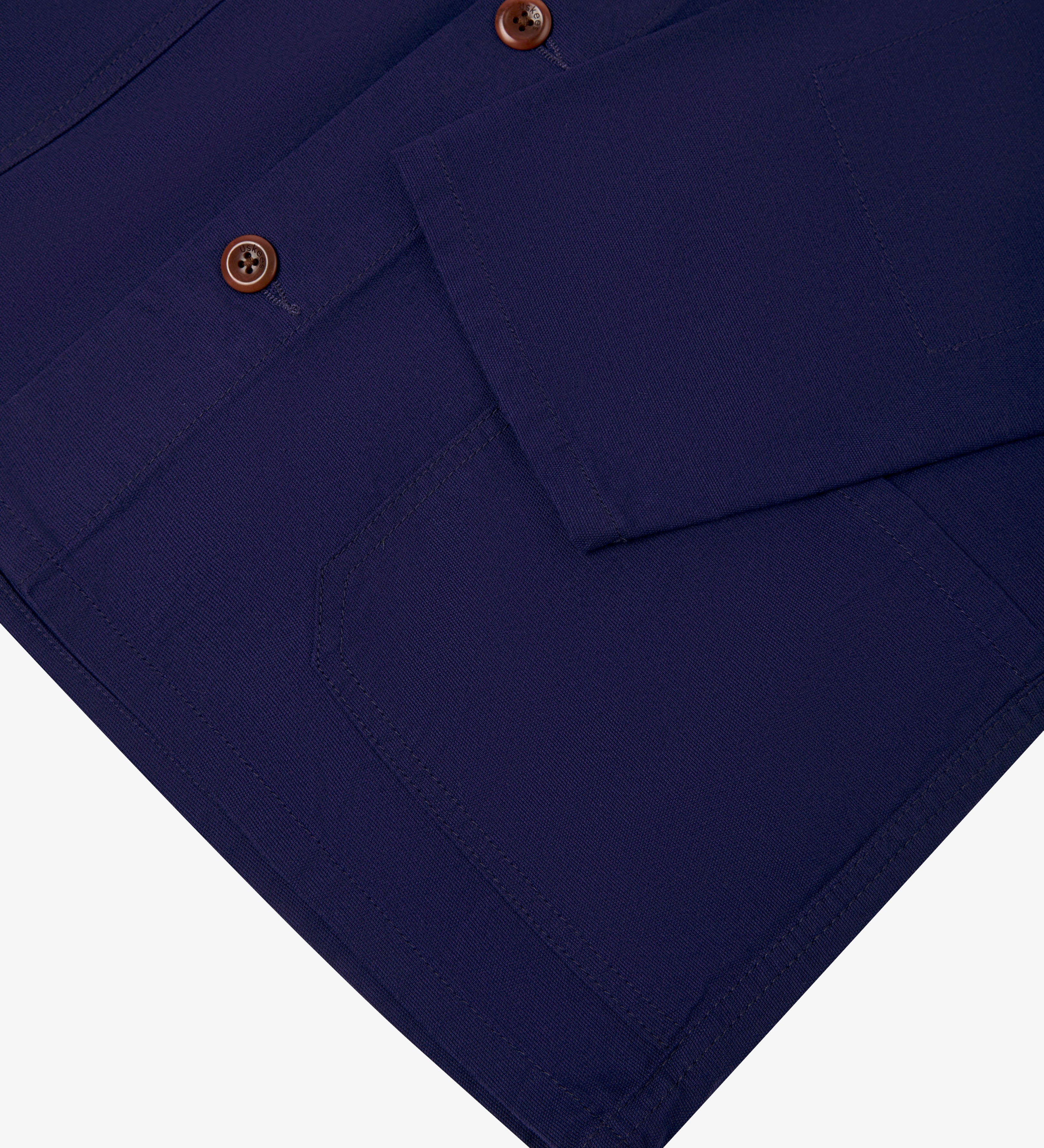 Closer view  of deep indigo, buttoned organic cotton overshirt from Uskees. Focus on cuff, placket, hip pocket and corozo buttons.