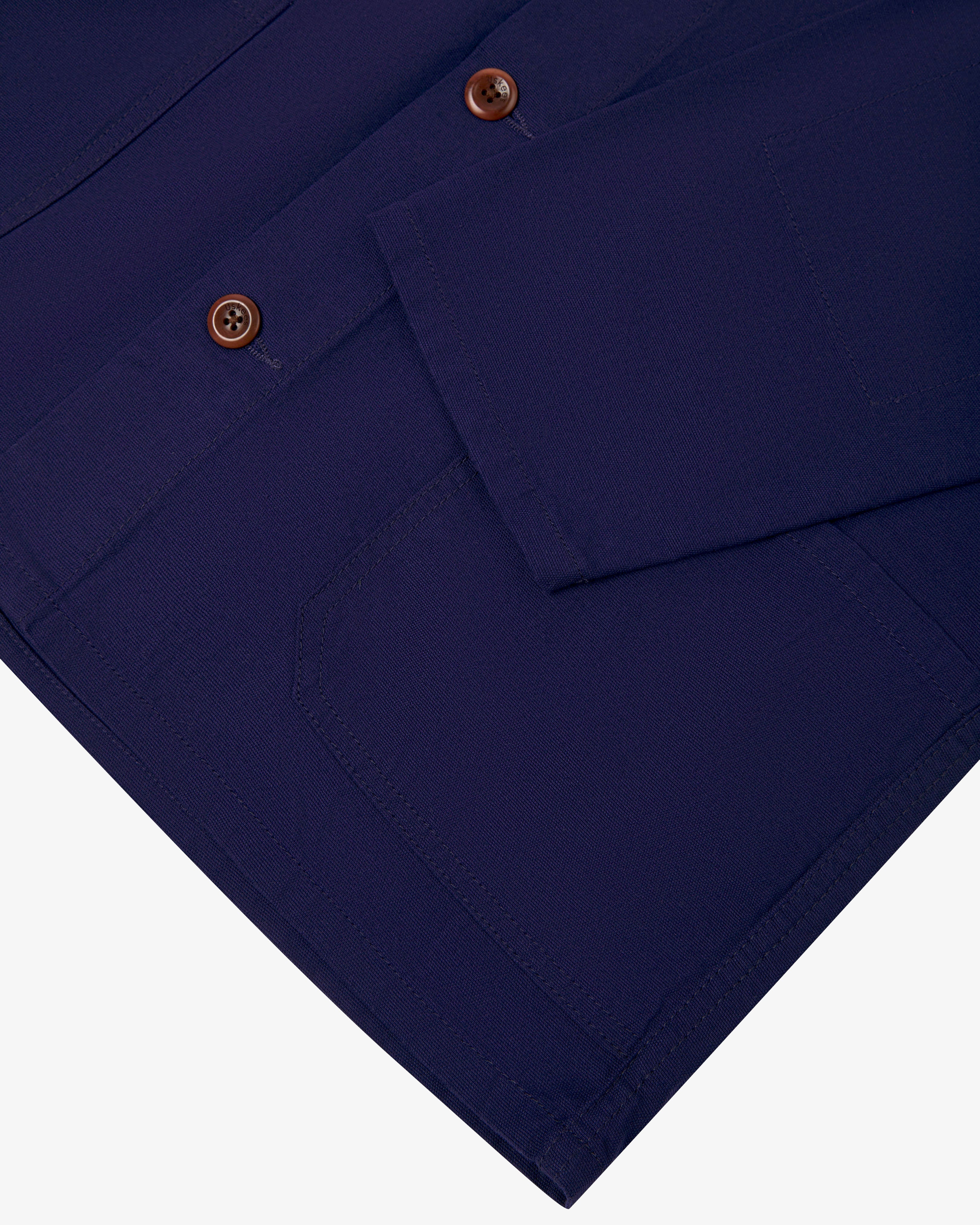 Closer view  of deep indigo, buttoned organic cotton overshirt from Uskees. Focus on cuff, placket, hip pocket and corozo buttons.