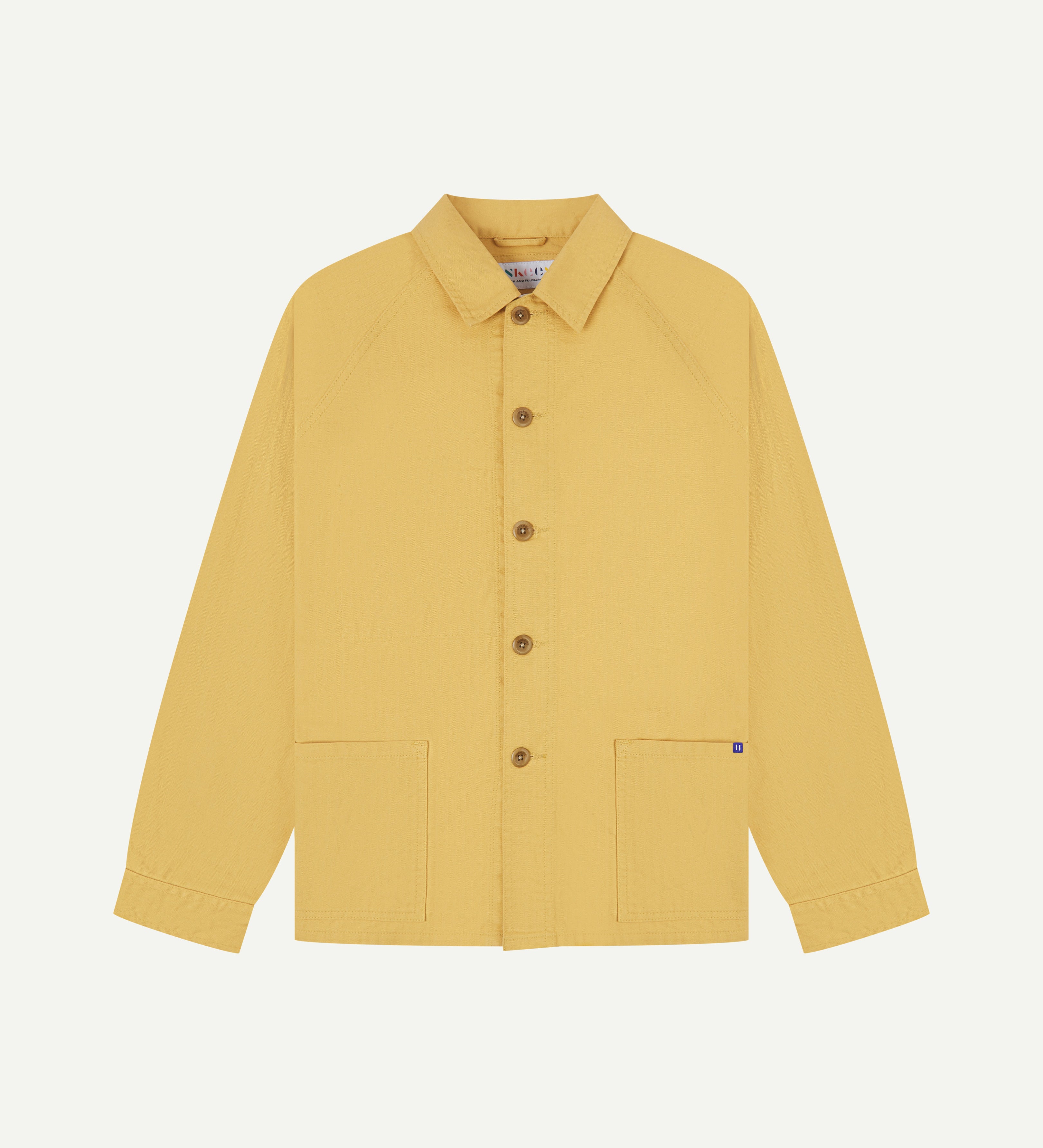 Flat front view of organic cotton sandstone-yellow signal jacket from Uskees. Clearly showing the corozo button fastening and 2 deep hip pockets.