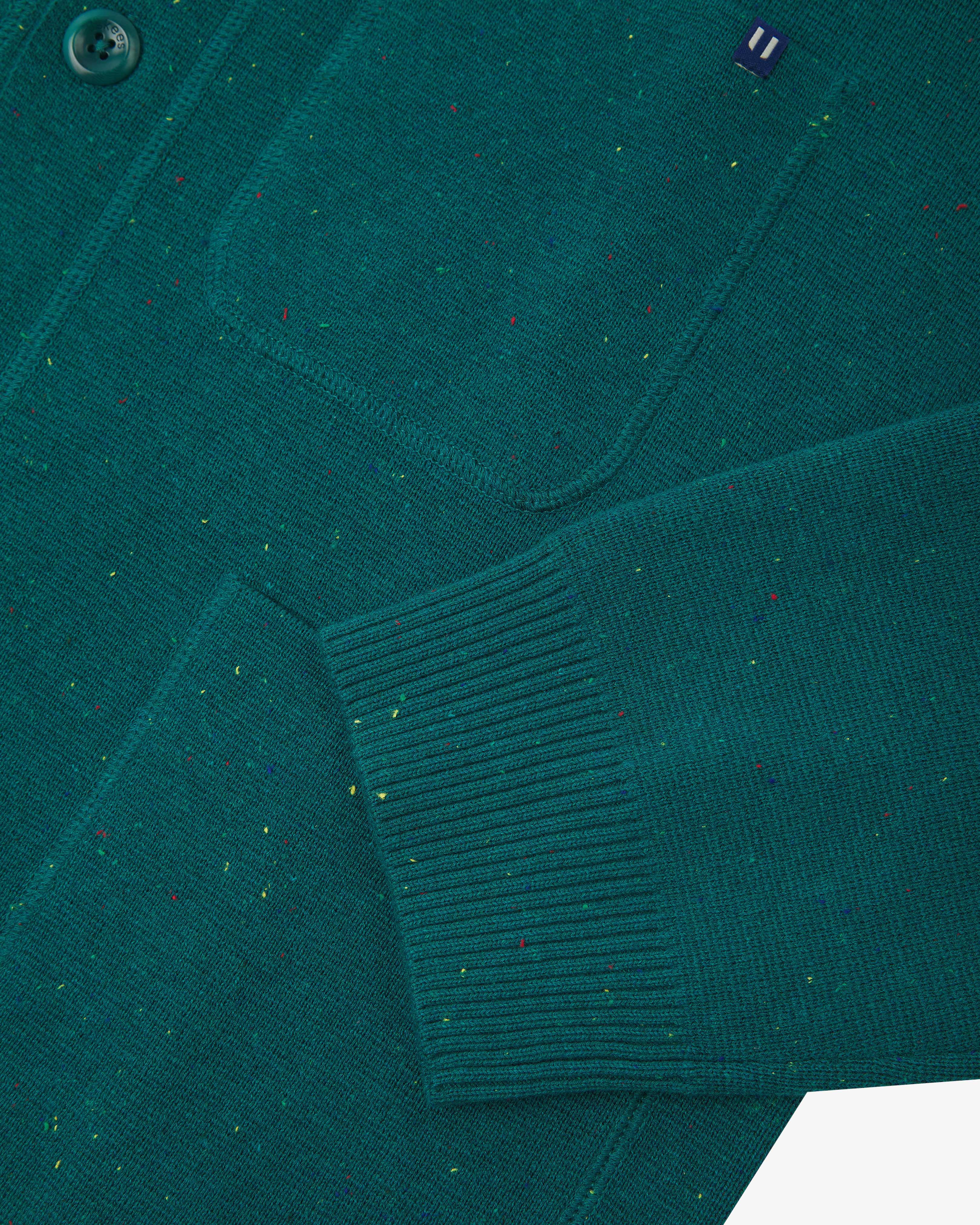 Close-up view of ribbed cuff and pockets of the knitted organic cotton, foam green cardigan from Uskees.