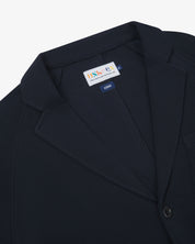 Close-up front view of knitted organic cotton midnight blue blazer showing the collar, lapels, corozo button and Uskees brand label.