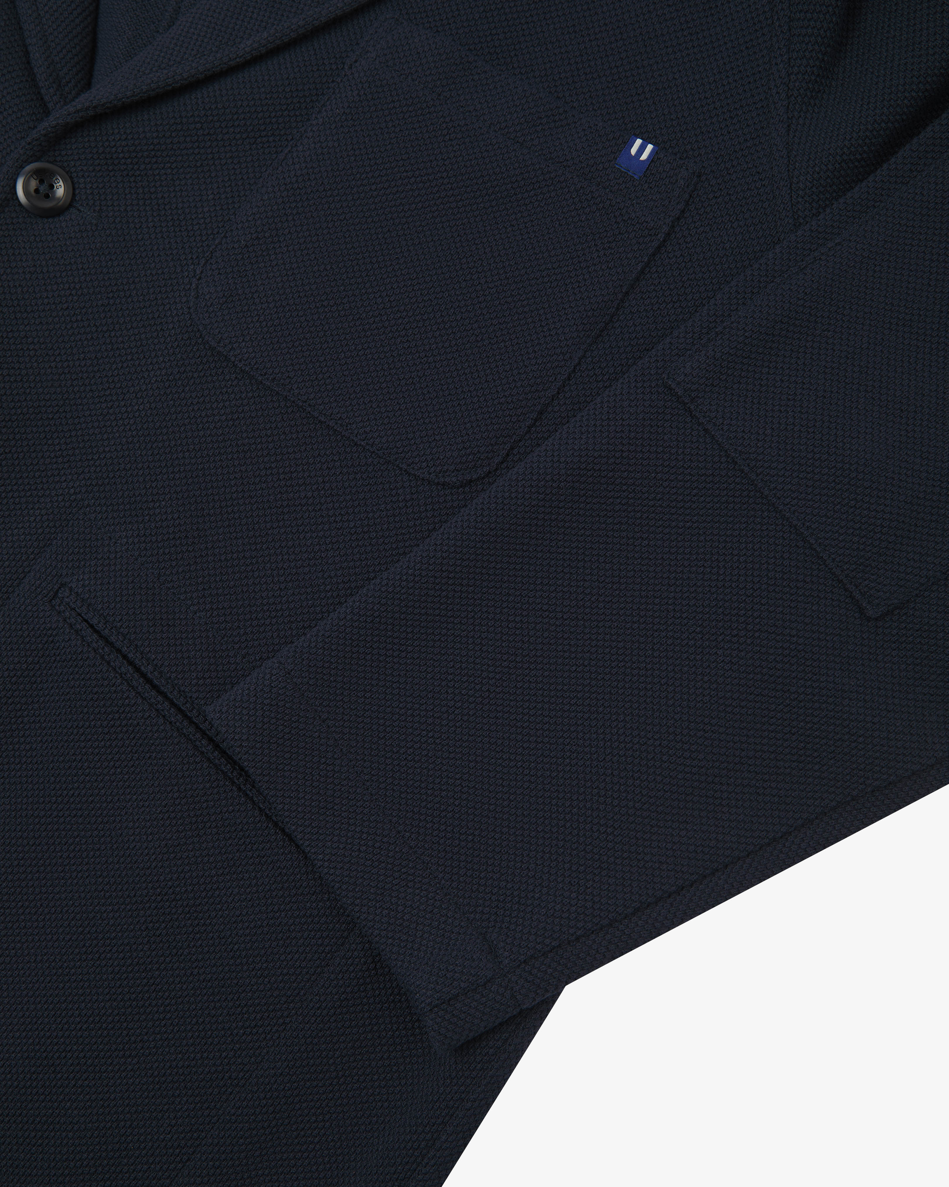 Close-up view of cuff and pockets of knitted organic cotton, midnight blue blazer from Uskees.