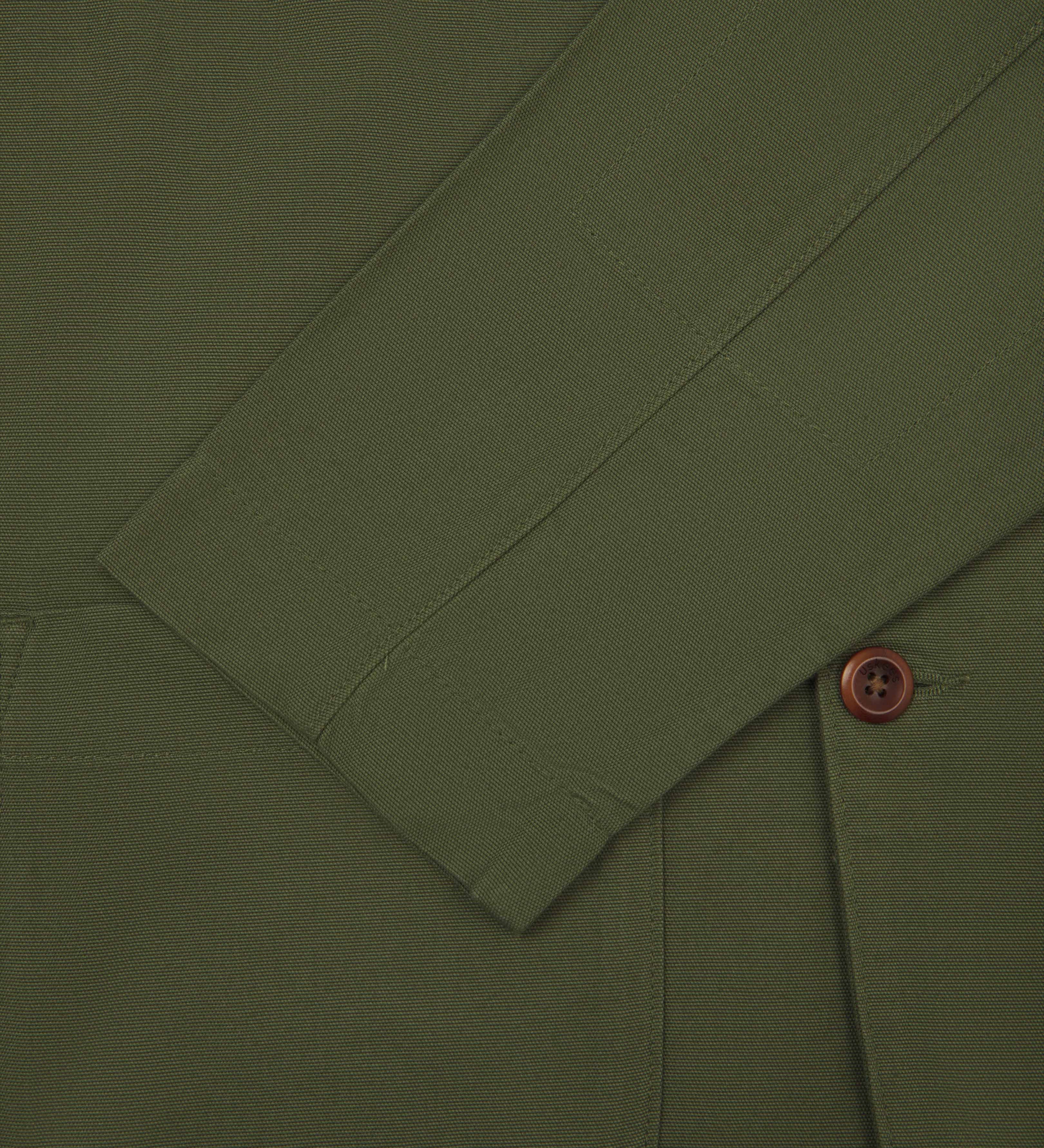 Close-up front view of coriander-green men's organic cotton blazer from Uskees showing sleeve, cuff and corozo button