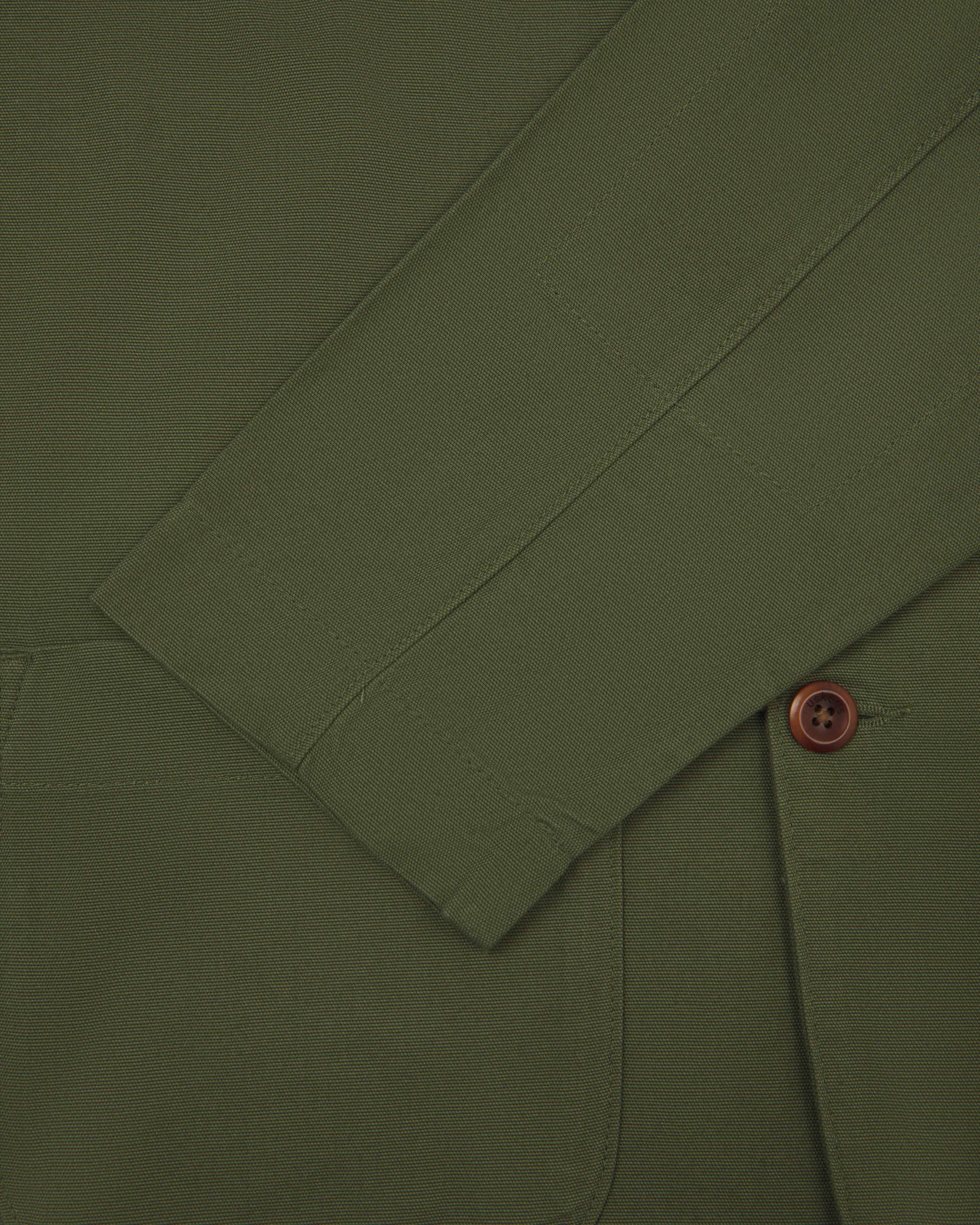 Close-up front view of coriander-green men's organic cotton blazer from Uskees showing sleeve, cuff and corozo button