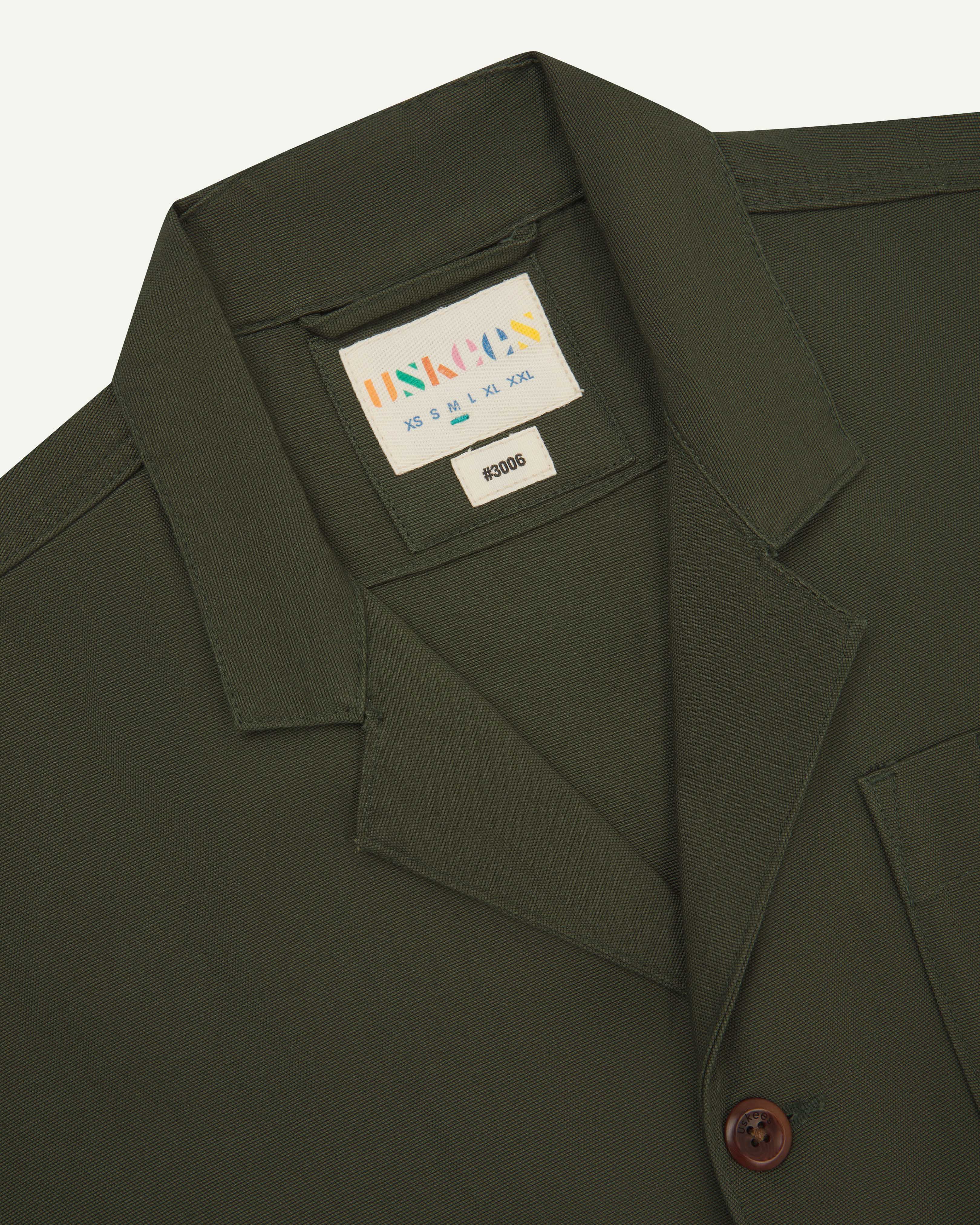 Close up front view of men's vine green blazer from uskees showing brand label at neck and collar.