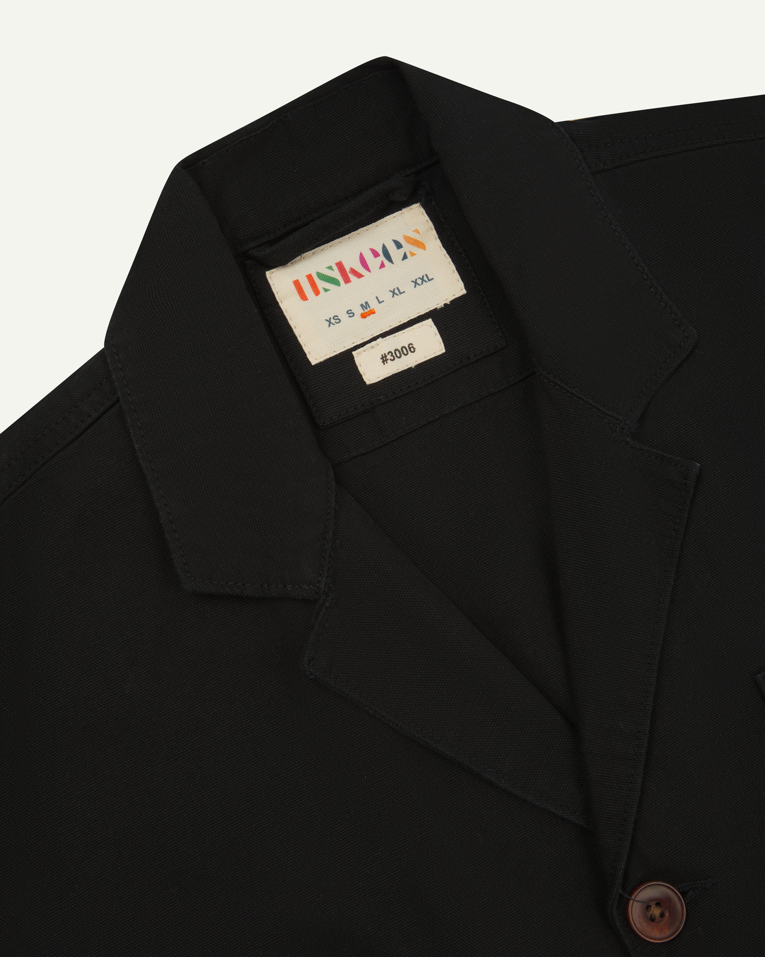Front close view of black blazer showing brand label and collar from Uskees.
