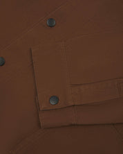 Close-up view of jacket popper fastening and matching cuff popper fastening of chocolate coloured Uskees coach jacket.
