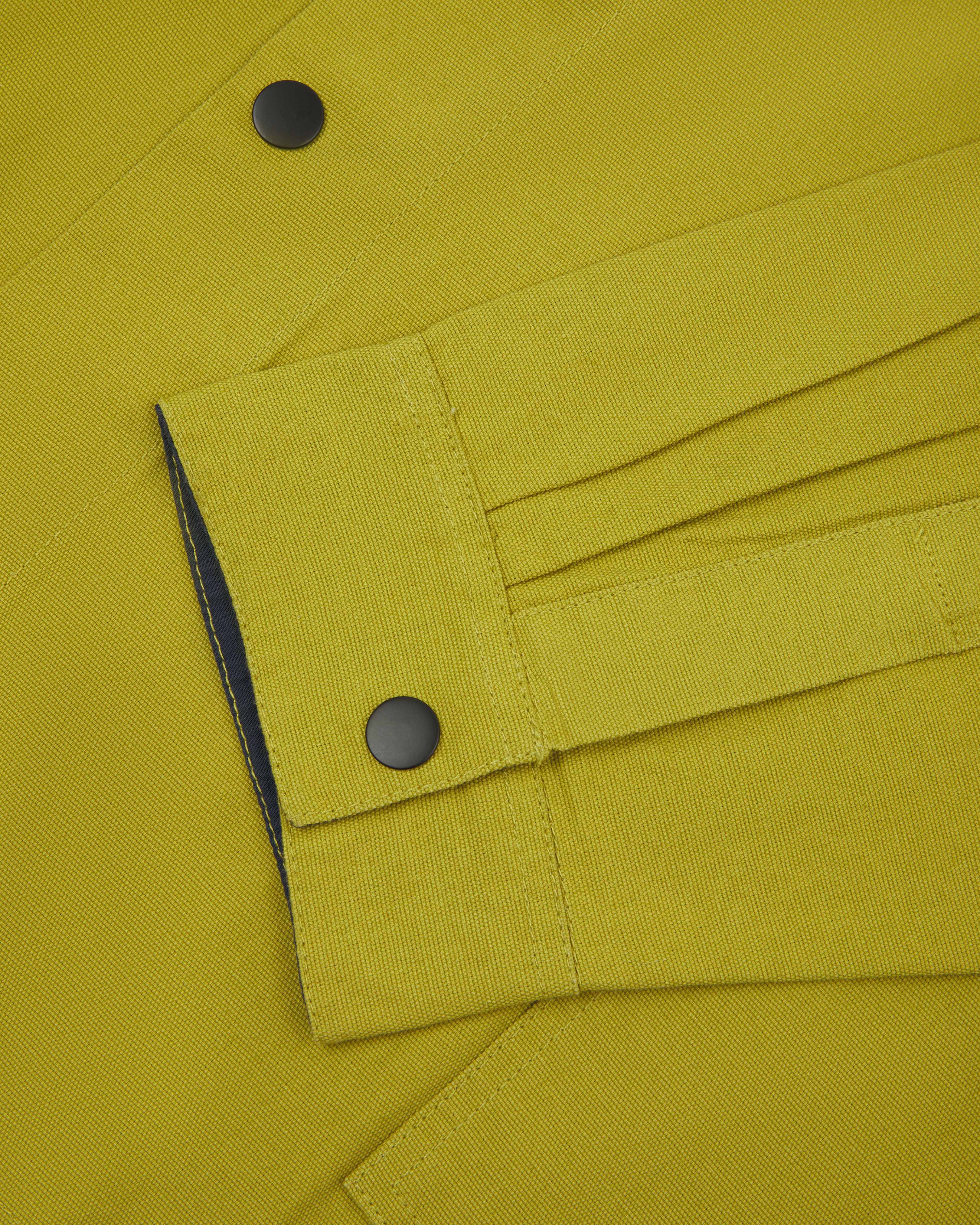 Close-up view of popper fastening and matching cuff popper fastening of pear coloured Uskees coach jacket.